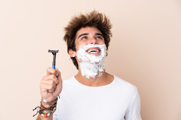 Seorang pria dengan kaos putih memegang sebuah alat cukur